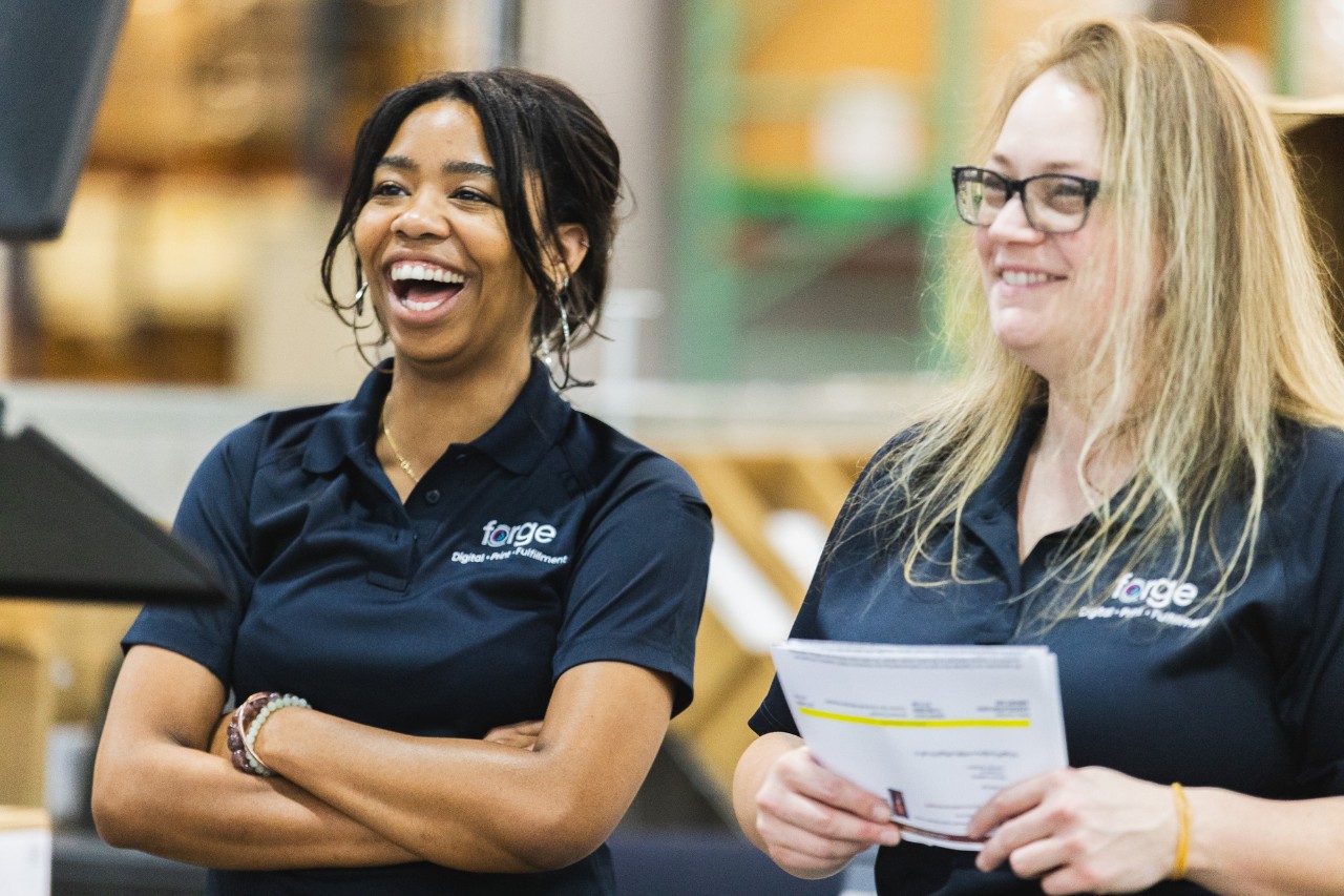 Two coworkers who are laughing, smiling, and talking with each other.